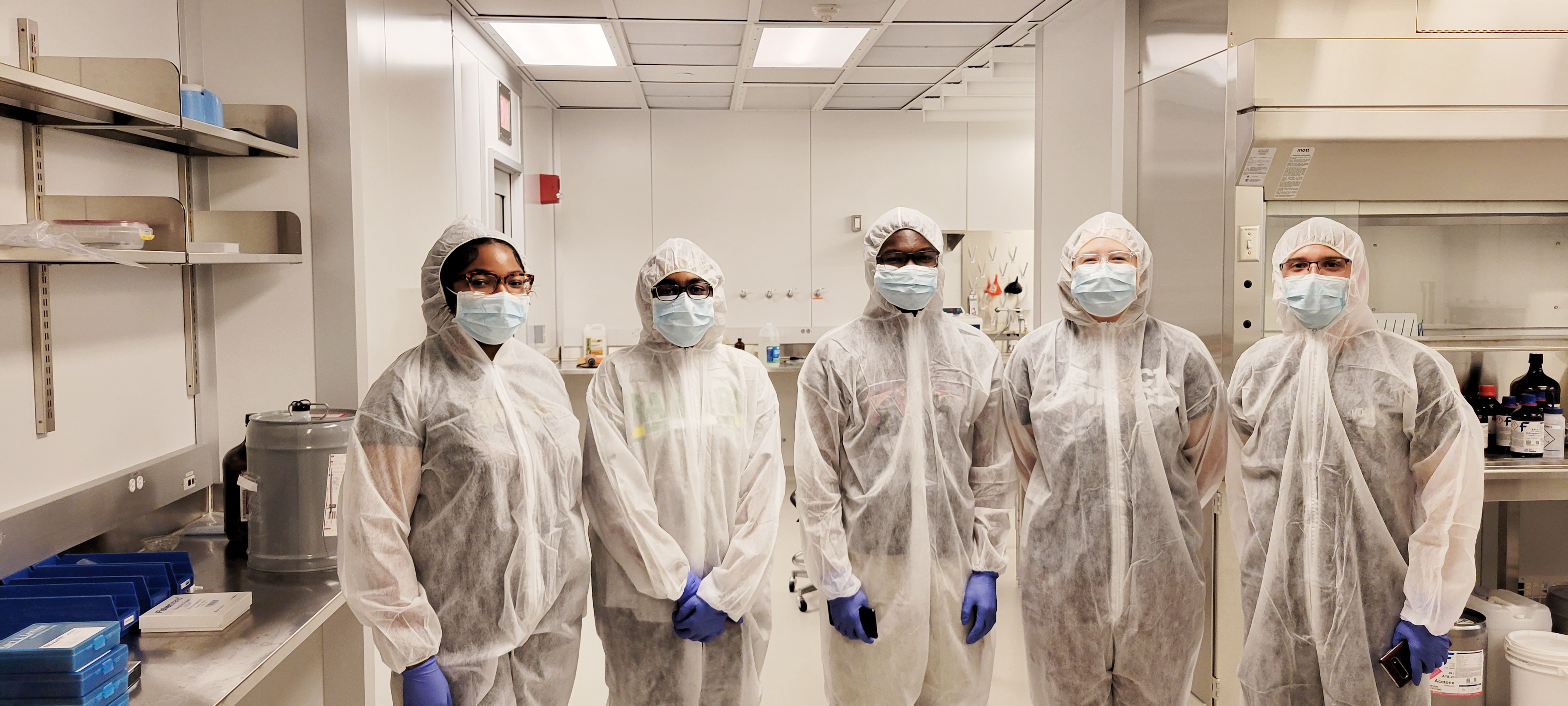 a group of researchers in protective gowns standing in a cleanroom